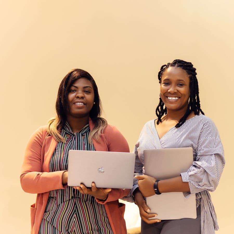 Two PrimeLogic consultants holding laptops