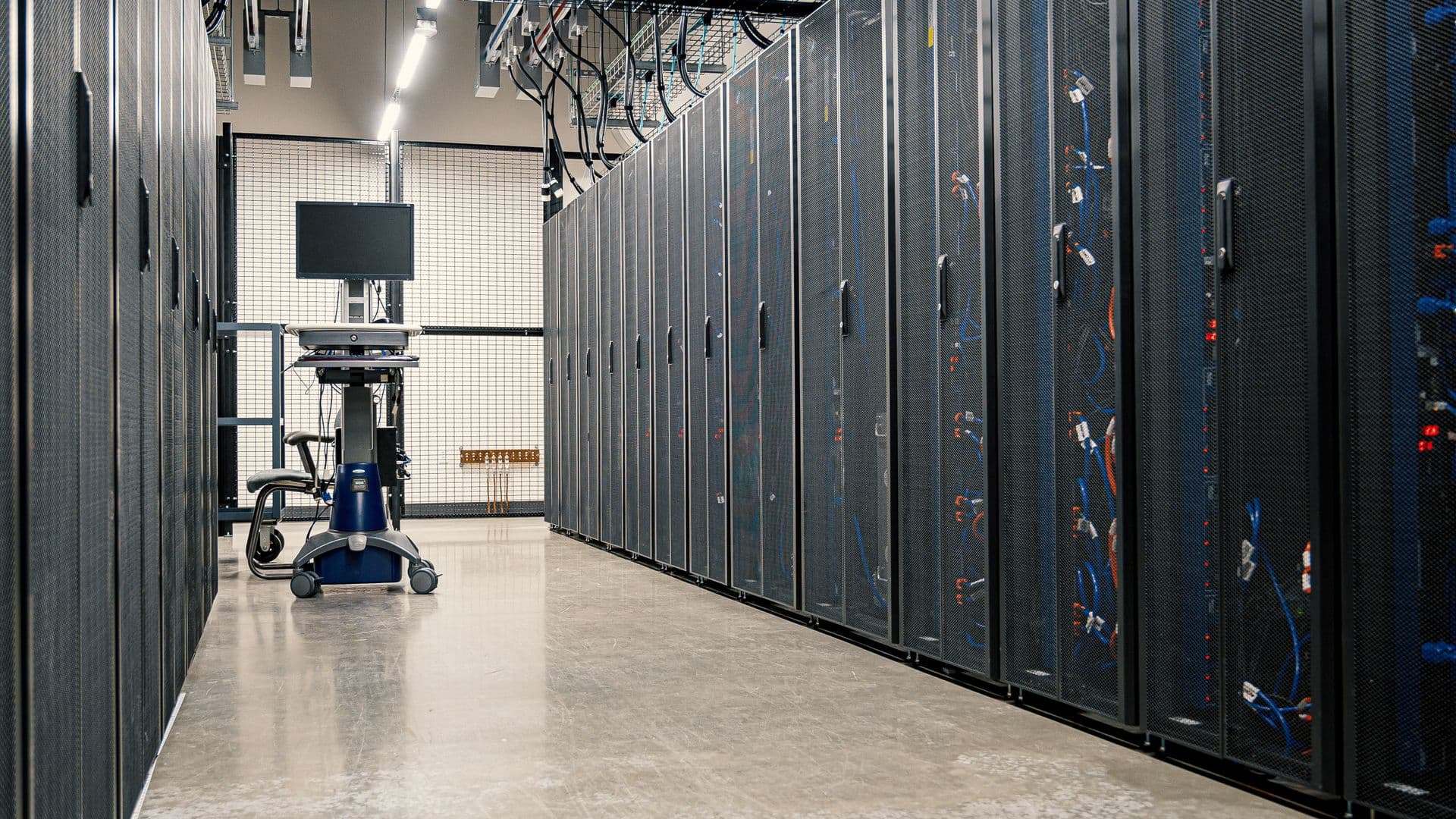 Rows of cabled server racks in a data centre aisle